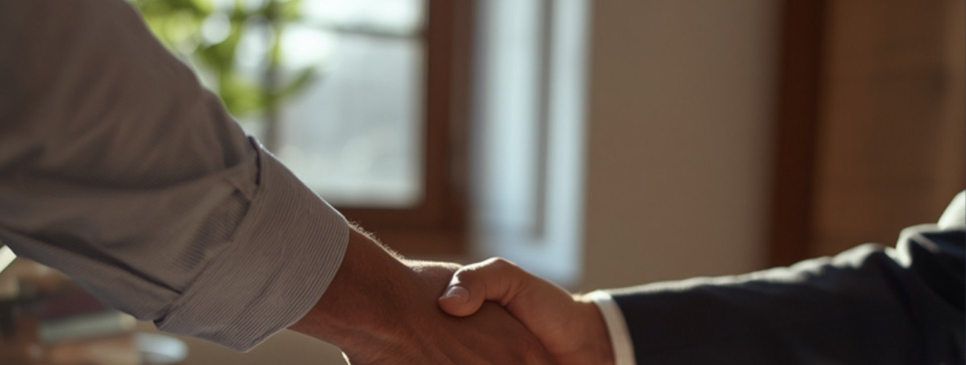 Two business people shaking hands over a desk
