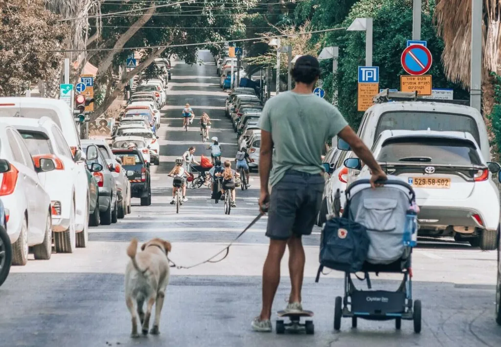 Man walking a baby and a dog whilst on a skateboard-yoav-aziz-unsplash